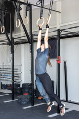 Athletic woman training on gymnastic rings indoors