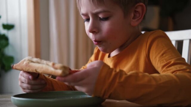 Cute healthy preschool kid boy eats a piece of cheese pizza for lunch. Charming child biting off big slice of fresh made pizza at the table in a restaurant indoor. Funny little toddler. Unhealthy food