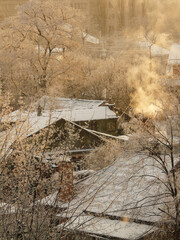 Snow-covered houses in countryside village on frosty morning, smoke peacefully rises from chimneys.