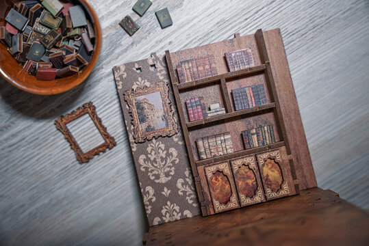Detailed miniature wooden library interior with spiral staircase, bookshelves and tiny furniture. Close-up of handcrafted dollhouse room showing creativity, hobby, craftsmanship and vintage design.