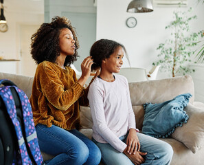 Portrait of happy mother and daughter having fun, mother combing daughters hair  and prepering her...