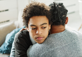 Portrait of son hugging his father, together at home. Son caring for his father, putting hand on...