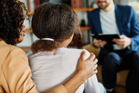 Mother with her teenage daughter at meeting with social worker, psychologist discussing mental health family sitting on sofa in psychotherapist office