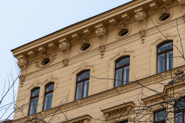 Obraz premium The upper part of the facade of a historic building with decorative windows and an ornamental cornice