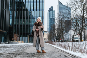 Winter city wanderlust: female tourist walking historic Warsaw old town, pastel facades and holiday lights, cozy coat, scarf and beanie. Urban sightseeing, slow travel, sustainable Europe escape eco.