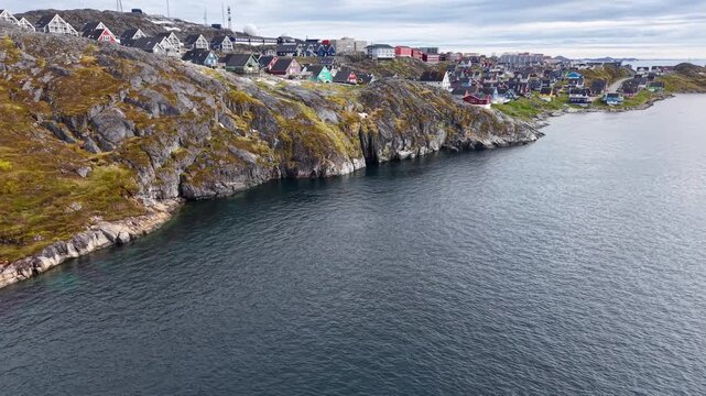 GREENLAND - 11.4.2025 - Fantastic aerial footage raising from the water up to reveal colorful buildings on the coast of Nuuk, Greenland.