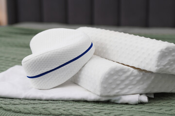 Clean orthopedic pillows and bedsheet on bed, closeup