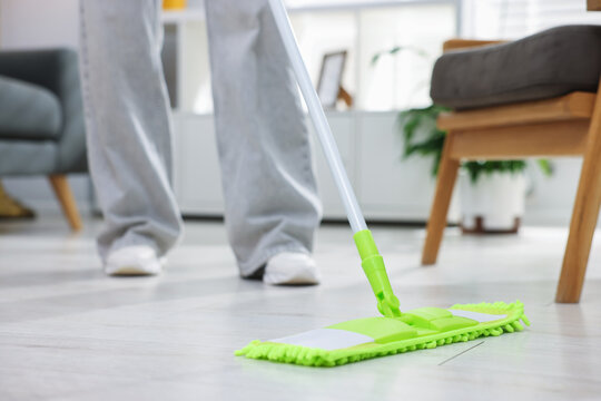 Woman cleaning floor with microfiber mop at home, closeup