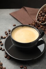 Obraz premium Aromatic coffee in cup and beans on grey table, closeup