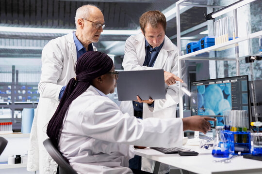 Group of scientists in chemistry lab conducting research study, using molecular analysis tools for experiment. Advanced healthcare, biotechnology research and medical discovery. - Powered by Adobe
