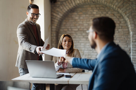 Professional business partners exchanging papers during a meeting
