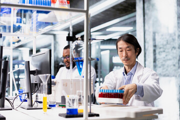Senior analytical chemist using scientific gear in research facility for complex experiments. Asian materials scientist in high tech laboratory doing genetics study using lab equipment