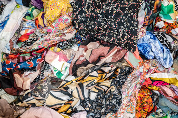 Close-up of mixed colorful fabric scraps in fashion studio, symbolizing textile design, reuse, creativity, and sustainable clothing production.