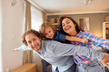 A family shares a fun moment together in their cozy living room. Parents smile as they playfully pose with their child, creating lasting memories of joy and love at home.