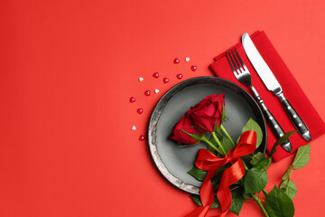 Beautiful table setting with roses and decorative hearts on red background, flat lay. Space for text