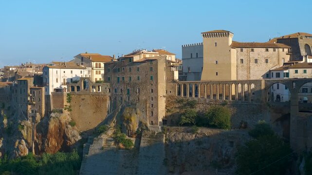 Medieval italian town of pitigliano panning at sunrise. Beautiful panoramic view of the medieval town of pitigliano in tuscany, italy, with its ancient houses built on a tuff rock cliff