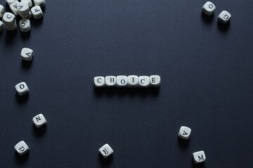 Minimalist conceptual image showing the word choice spelled with white letter blocks on a dark background, surrounded by scattered letters. Represents decision making, options, risk with copy space.
