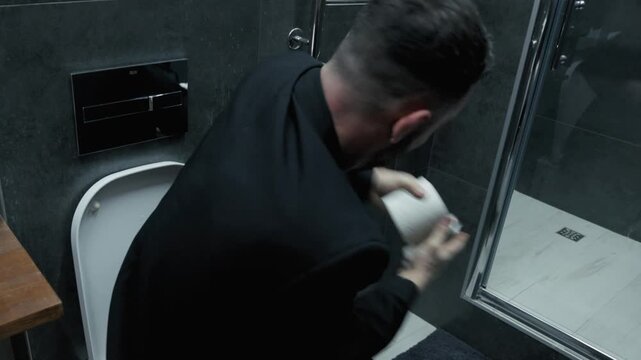 A businessman experiences discomfort and indigestion while working in a modern office. A business man with a tense expression sits on the toilet, suffering from diarrhea and abdominal pain.