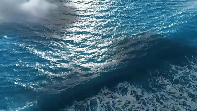 Dynamic Ocean Surface with Sparkling Sunlight - A Top-Down View of Rhythmic Waves and Foamy Crests Against a Dark Background