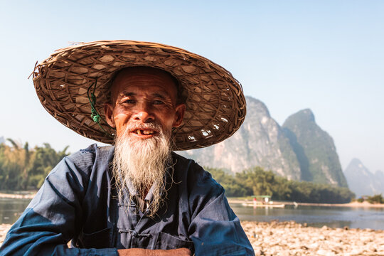 Portrait of old chinese man with straw hat on the Li river, China