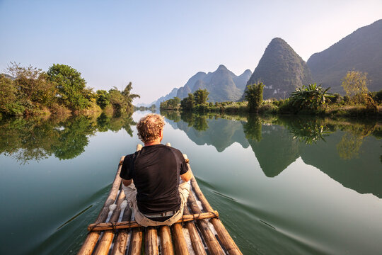 Tourists on bamboo boat on the Li river looking at karst peaks, Guilin, China