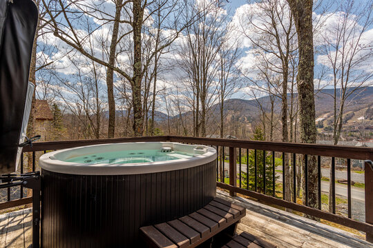 Mountain cabin deck with outdoor hot tub and scenic forest valley view