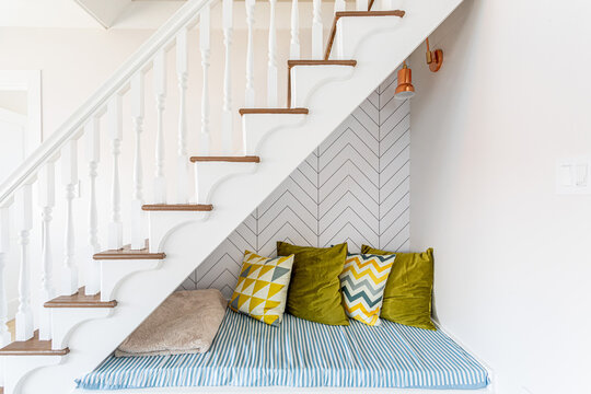 Cozy under-stair seating nook with patterned cushions and modern wall design
