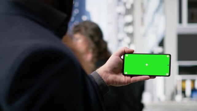 Horizontal chroma key phone of casual man walking outdoors on busy street, multicultural city life, everyday movement and the active routine of a dynamic urban crowd. Metropolitan area. Camera B.