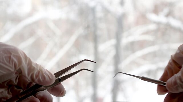 Detailed view of a hand holding precision tools during an eyelash extension procedure in beauty salon