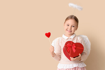 Naklejka premium Cute little girl dressed as cupid with heart and gift box on beige background. Valentine's Day celebration