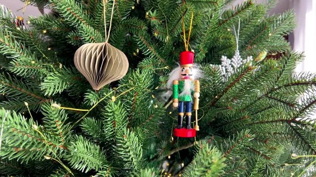  Wooden Nutcracker Christmas ornament hanging on a decorated Christmas tree. Traditional holiday decor with festive lights and classic New Year atmosphere, winter celebration and seasonal decoration