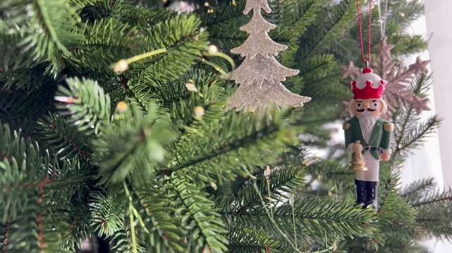 Wooden Nutcracker Christmas ornament hanging on a decorated Christmas tree. Traditional holiday decor with festive lights and classic New Year atmosphere, winter celebration 