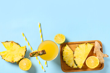 Glass of fresh pineapple juice with lemon and ginger root on blue background
