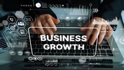 Hands Typing on Laptop Keypad Surrounded by Digital Graphics Indicating Business Growth and Data...