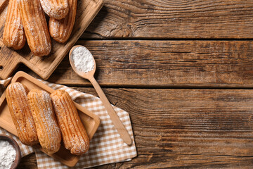 Boards with tasty eclairs and sugar powder on wooden background
