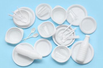 Different plastic tableware and cutlery on blue background