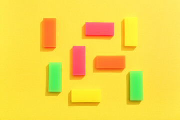 Colorful rubber erasers on yellow background