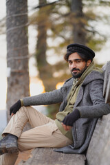 Obraz premium Man in traditional cap and winter coat sitting in a forest. Ideal for travel, cultural lifestyle, and nature concepts.