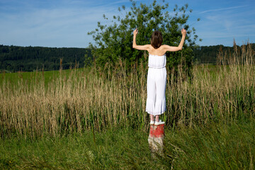 Woman raising arms in meadow enjoying summer nature

