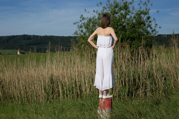 Woman standing in meadow seen from behind on sunny day
