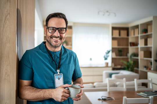 Male doctor or nurse smiling and holding coffee cup