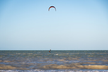 ide shot of an athletic woman kitesurfing in the sea.