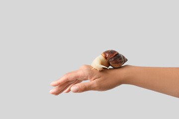 Female hand with snail on grey background © Pixel-Shot