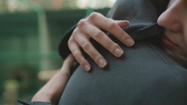 closeup hand on jacket shoulder detailed support gesture fingers resting gently subtle pressure texture of wool coat urban background blur mood of reassurance calm caregiver or partner comforting