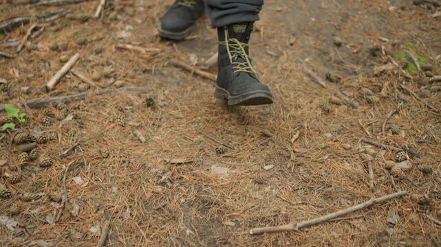 boots stepping across pine needle carpet with sure footing, park ranger patrolling trail, yellowlaced boots, closeup of soles moving over sticks and soft soil, focused outdoor inspection