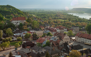 Panoramic view of a historic European town with traditional rooftops, old market square, church on the hill and a wide river valley surrounded by green landscape on a sunny day