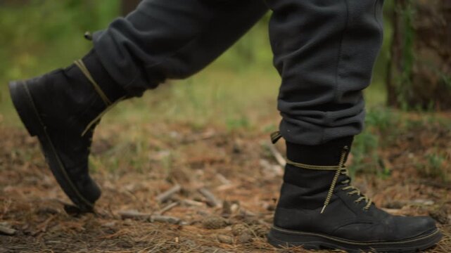 lowangle hiking boot crossing mossy trail, firm rhythmic steps beneath pine canopy, yellow laces and dark boots, gray joggers brushing bark and twig litter, energetic morning trek through green