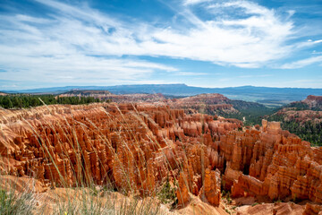 A beautiful, rocky landscape with a blue sky in the background. The rocks are orange and the grass is green, creating a striking contrast. The scene is peaceful and serene
