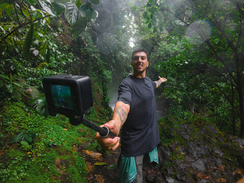 UGC-style video of a man using an action camera to document his journey through a lush forest or jungle.