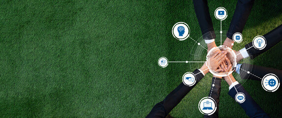 Aerial view of diverse hands uniting on a green grass surface, surrounded by digital icons symbolizing innovation, creativity, and teamwork in a modern professional context. Amity